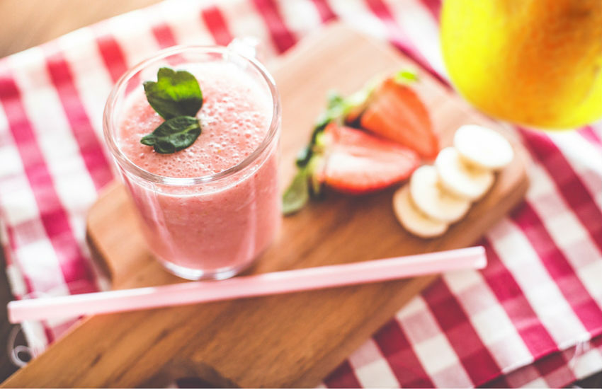 A glass of fruit smoothie with strawberries, banana and melon.
